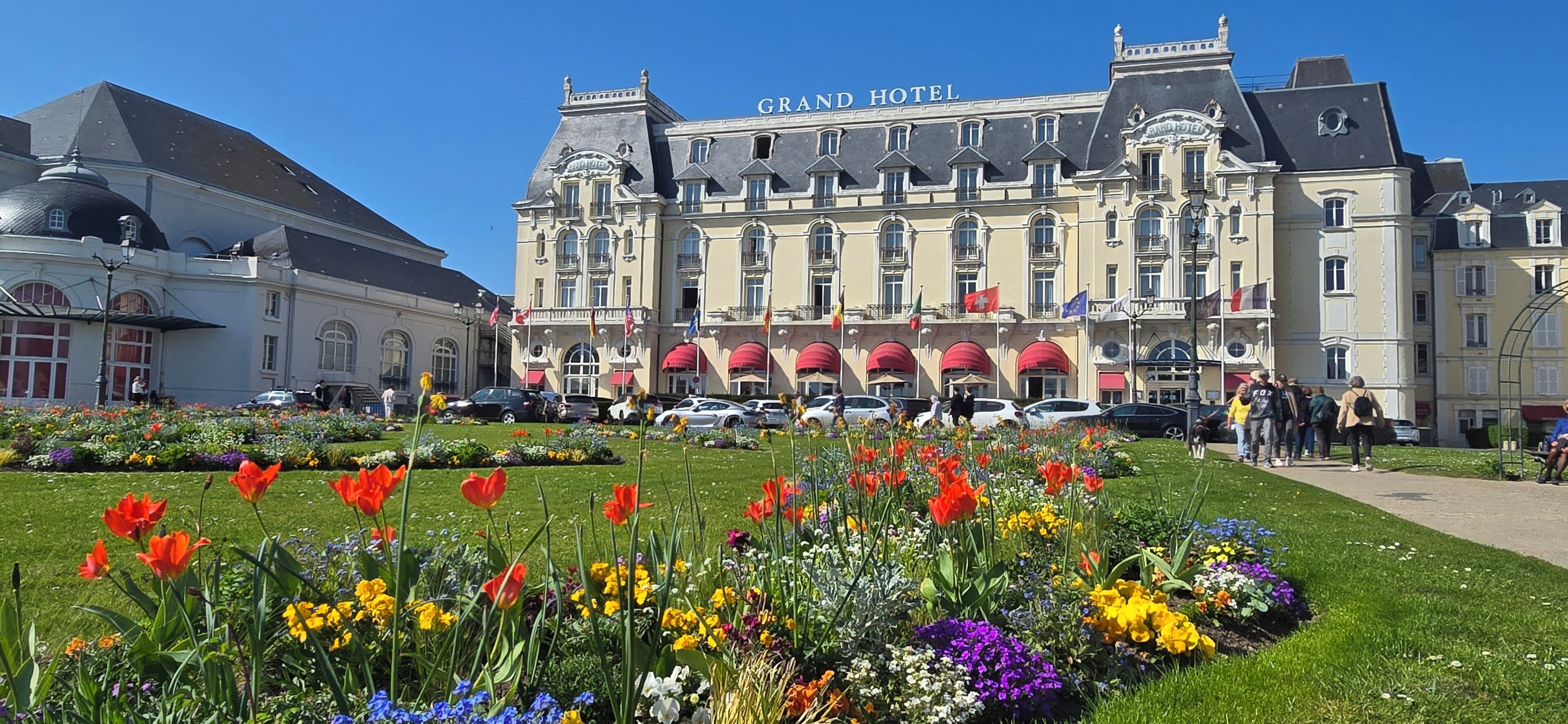 Un grand hôtel doté d’un vaste jardin à l’avant, où l’on peut admirer une grande variété de fleurs et une pelouse parfaitement entretenue.