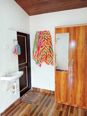 Un baño con lavamanos blanco, armario de madera y toallas coloridas en la pared.