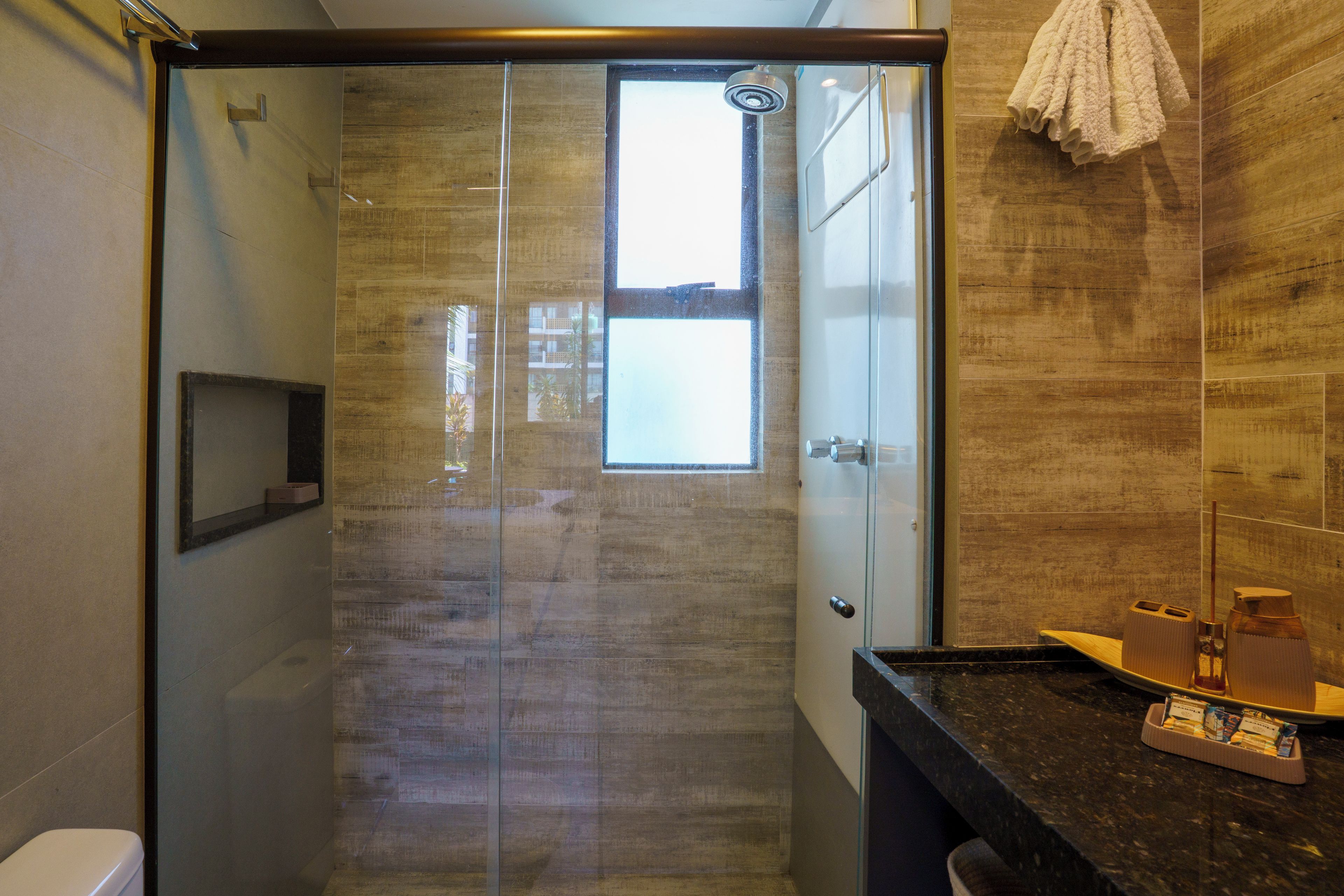 A modern bathroom with a glass-enclosed shower, a black countertop, and a towel rack.