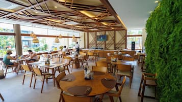 A restaurant with wooden tables and chairs, a green wall, and a TV mounted on the wall.