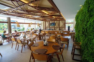 A restaurant with wooden tables and chairs, a green wall, and a TV mounted on the wall.