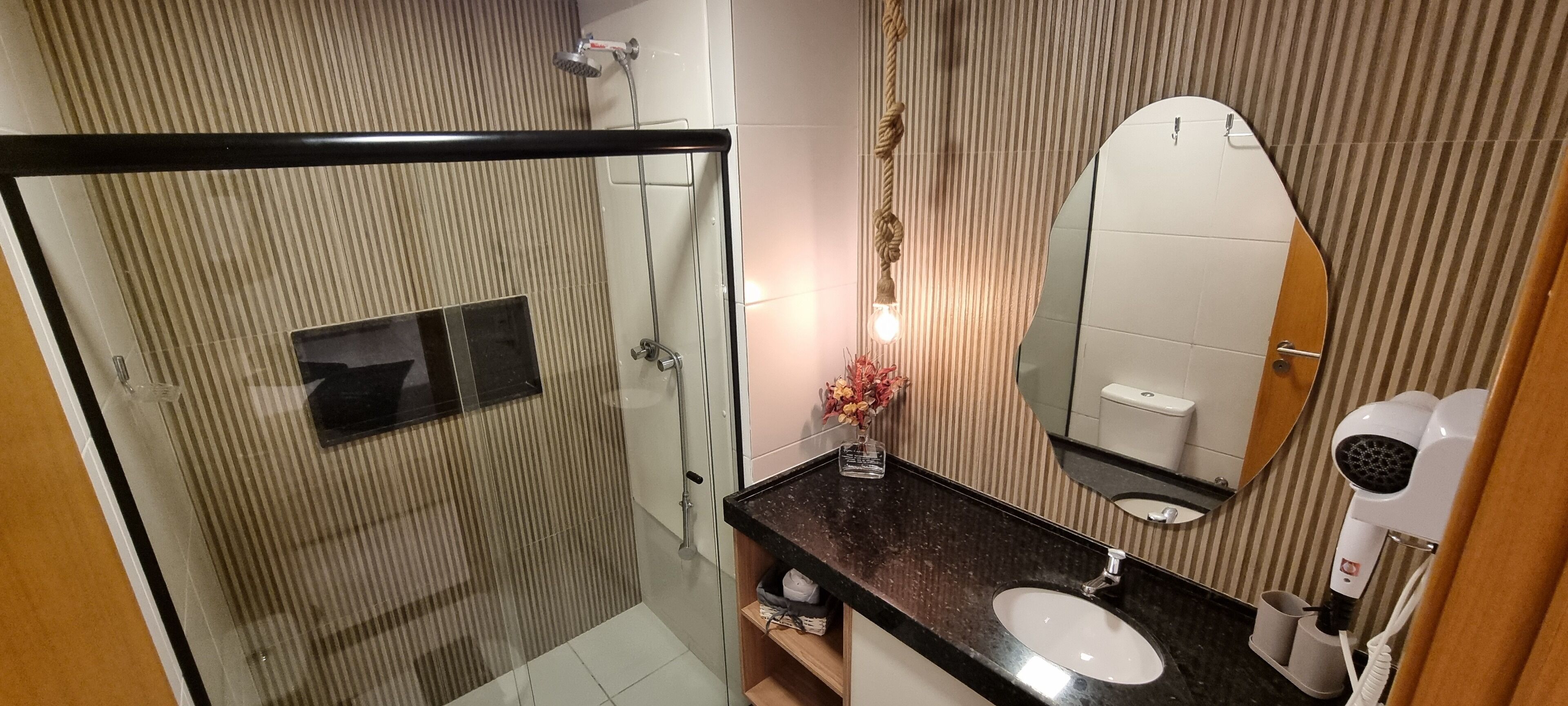 A modern bathroom with a glass-enclosed shower, a large mirror, and a hairdryer.
