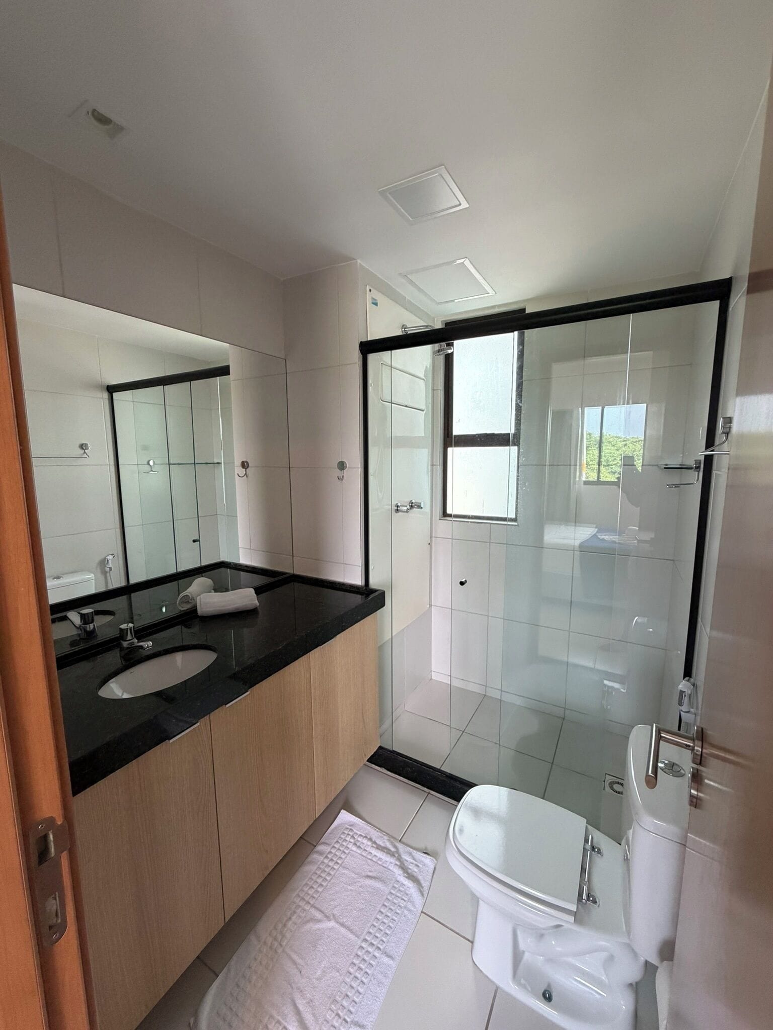 Une salle de bain moderne avec une douche à parois de verre, un lavabo doté d’un plan de toilette noir et des toilettes.