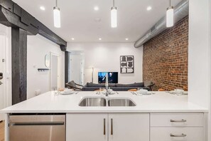 A modern kitchen with a large island, stainless steel appliances, and a brick accent wall.