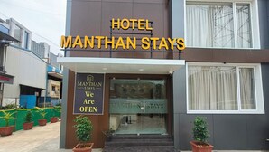 L’entrée d’un hôtel, avec une enseigne indiquant « Hotel Manthan Stays » et une banderole annonçant « Nous sommes ouverts ».