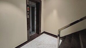 Un couloir doté d’un sol en marbre menant à un ascenseur.