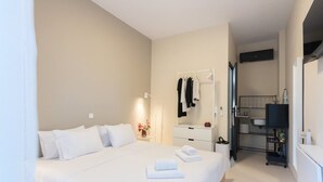 A hotel room with a large bed, a bedside table with a lamp, a wardrobe, and a bathroom visible through an open door. - Astra Beach Studio 2 (Pylos-Nestoras)
