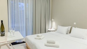A hotel room with a bed, a bedside table with a bottle and glasses, and a window with curtains. - Astra Beach Studio 4 (Pylos-Nestoras)