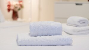 A neatly made bed with two rolled white towels and a folded towel in the background. - Astra Beach Studio 5 (Pylos-Nestoras)