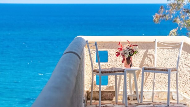 A terrace with a view of the sea, featuring two white chairs and a table with a vase of flowers. - Astra Beach Studio 5 (Pylos-Nestoras)