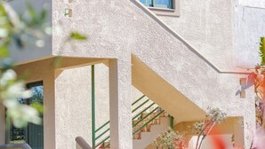 A modern building with a staircase leading to a second floor, surrounded by plants and a clear sky. - Astra Beach Studio 5 (Pylos-Nestoras)