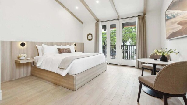 Una camera da letto moderna con un letto, un comodino e vista sull'esterno attraverso una porta in vetro.