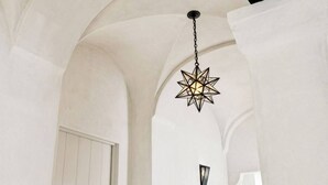 Una lampada a sospensione a forma di stella in una stanza dalle pareti bianche e soffitto ad arco.