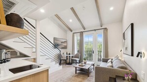 Un appartamento moderno con cucina, zona pranzo e soggiorno. Dispone di una scala, un balcone con vista e un'ampia finestra.