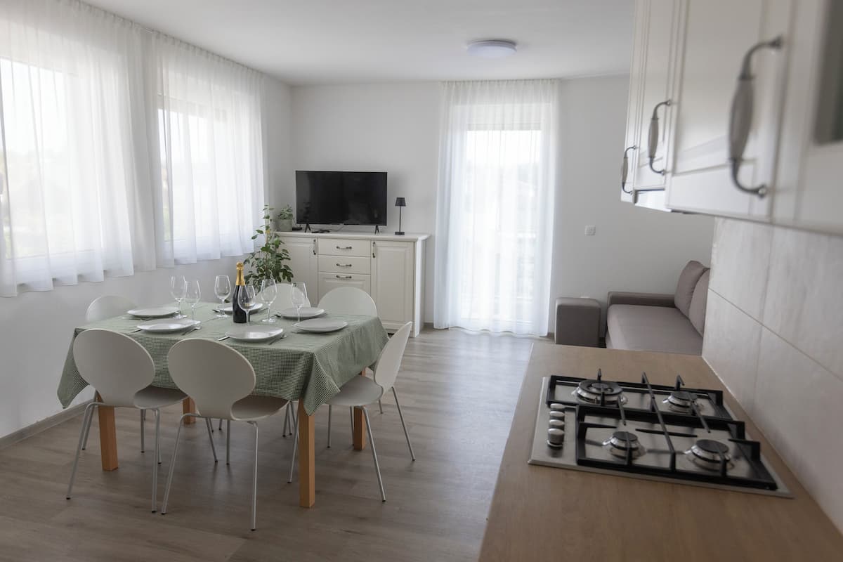 Una cocina moderna con estufa a gas, alacenas blancas y un comedor con mesa para cuatro.