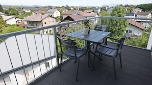 A balcony with a table and chairs, overlooking a residential area with houses and greenery. - Villa Andrea Apartments - Ljubljana (Ljubljana)
