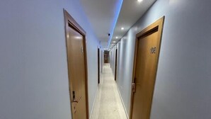 A long, narrow hallway with wooden doors on both sides, leading to rooms.