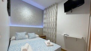 A modern bedroom with a large bed, a flat-screen TV, and a built-in sound system.