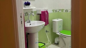 A bathroom with a white sink, a mirror, a toilet, and a green trash bin. - Hotel Dar Ali  (Tunis)