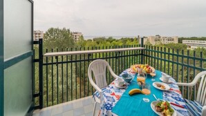 Ein Balkon mit Frühstückstisch, gedeckt mit Obst, Brot und Getränken.
