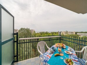 Ein Balkon mit Frühstückstisch, gedeckt mit Obst, Brot und Getränken.