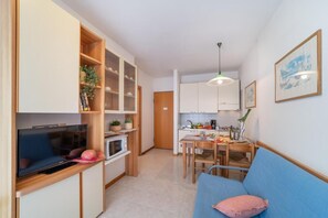 Ein kompakter Wohnbereich mit Küchenzeile, Essplatz und einer Couch.