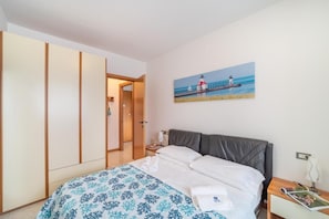 Ein Hotelzimmer mit Bett, Nachttisch, einem Gemälde eines Leuchtturms und einem Kleiderschrank.