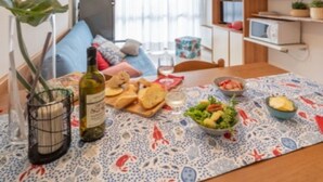 Ein modernes Wohnzimmer mit Esstisch, gedecktem Tisch für eine Mahlzeit, einer Couch und einer Küchenzeile mit Schränken und einer Mikrowelle.