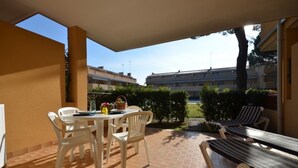 A patio with a table and chairs, a bench, and a view of buildings in the background. - Centric flat with pool (Bibione)