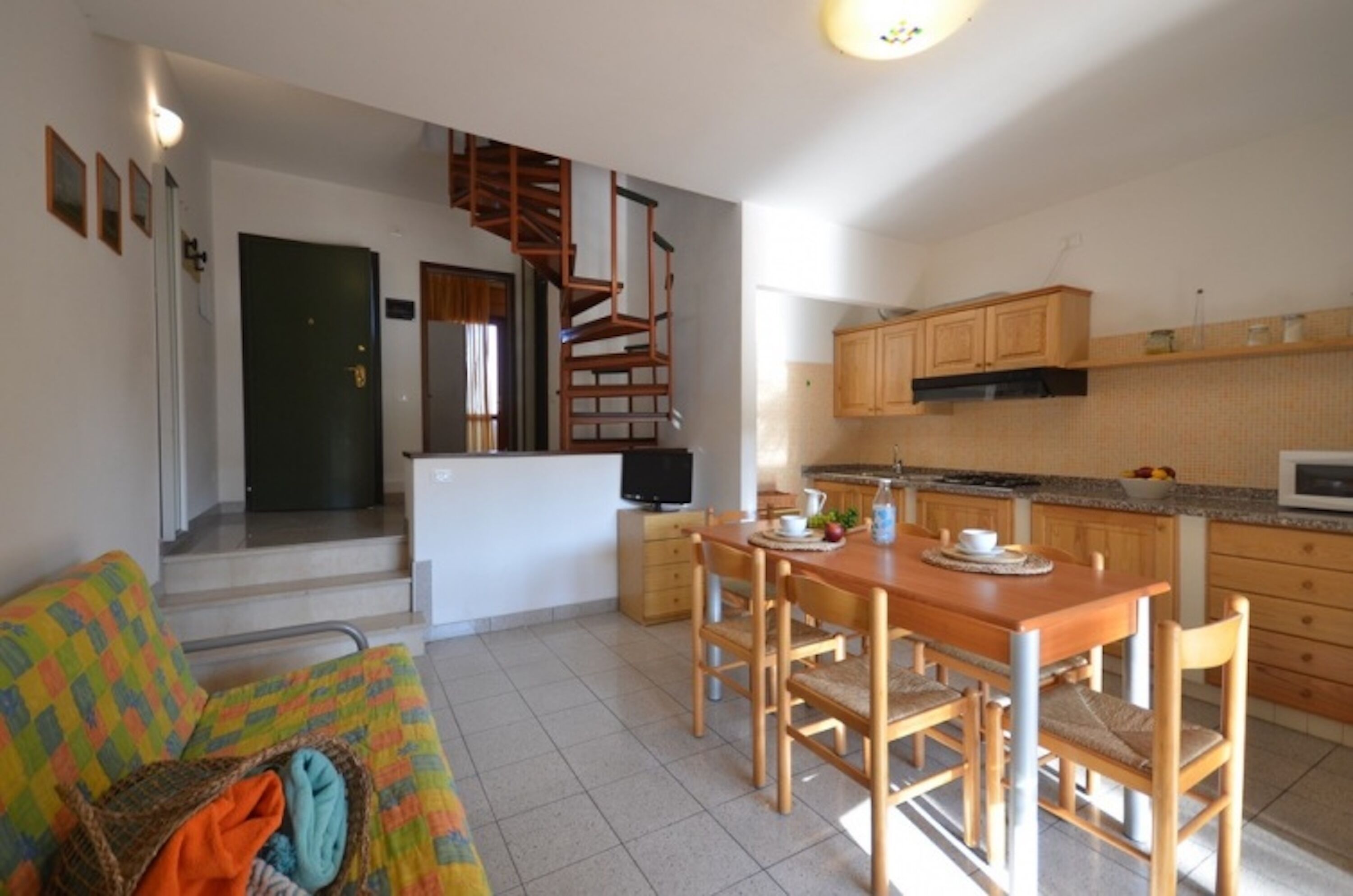 A compact living space with a dining area, kitchenette, and a staircase leading to an upper level.