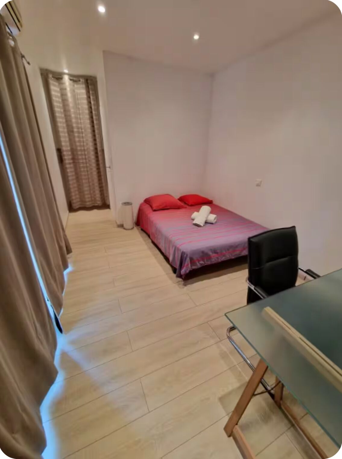 Une petite chambre à coucher, bien rangée, avec un lit, une chaise et un bureau.