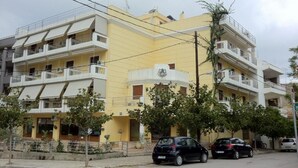 A multi-story residential building with balconies, a yellow facade, and parked cars on the street. - Hotel Magnolia (Istiaia-Aidipsos)