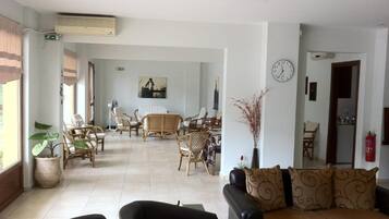 A spacious living area with a sofa, chairs, a dining table, and a kitchen in the background.