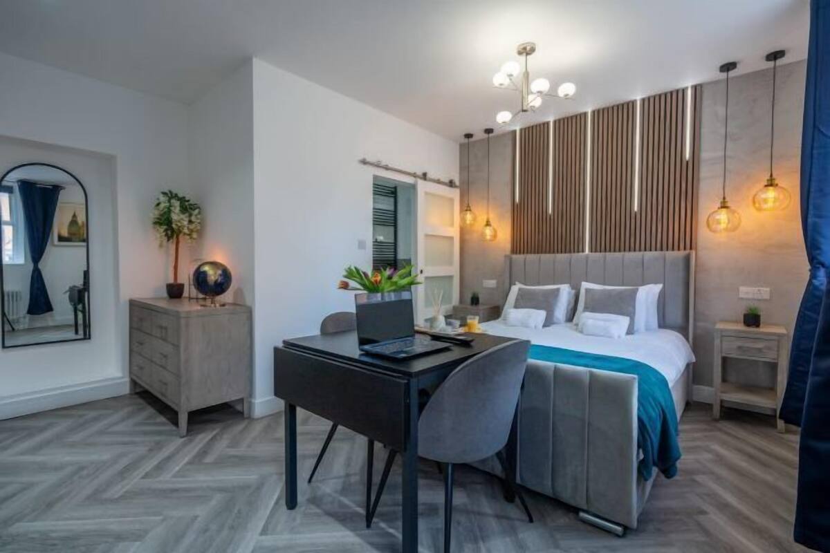 A modern bedroom with a bed, desk, chair, and bedside tables.