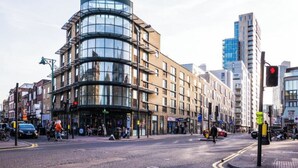 A modern building with a curved glass facade, a pedestrian crossing, and a traffic light. - Shoreditch Luxe (London)