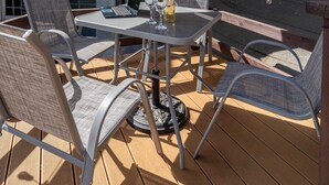 An outdoor patio with a table, chairs, a laptop, a bottle, and an umbrella. - Shoreditch Luxe (London)