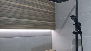 A modern shower with a rain showerhead and handheld showerhead, a wooden panel wall, and tiled walls.