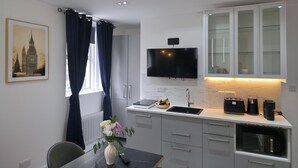A modern kitchen with a flat-screen TV, a built-in oven, and a dining area with a table and chairs.