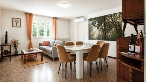 A living room with a sofa, coffee table, and dining table with chairs. There is a TV, a vase with flowers, and a painting on the wall. - Beautiful home in Sablet (Sablet)