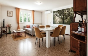 A living room with a sofa, coffee table, and dining table with chairs. There is a TV, a vase with flowers, and a painting on the wall. - Beautiful home in Sablet (Sablet)