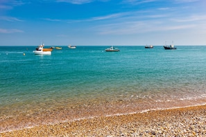 A beach with pebbles and boats in the water. - Historic Railway Home - Selsey Seafront (Chichester)
