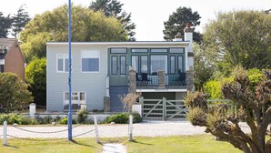 A two-story house with a balcony, a gated entrance, and a pathway leading to the front door. - Historic Railway Home - Selsey Seafront (Chichester)