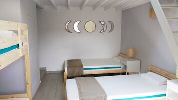 Une chambre avec des lits superposés, un bureau et un mur décoré de motifs représentant les phases de la lune.