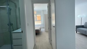 A modern, well-lit hallway with a glass shower enclosure, a white wardrobe, and a grey sofa in a contemporary apartment setting. - TERRASOL MONTERREY 2ªB7 (Torre del Mar)