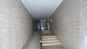 A hallway with tiled walls and a wooden handrail, leading to a staircase. - TERRASOL MONTERREY 2ªB7 (Torre del Mar)