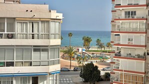 A coastal building with balconies overlooking the sea, a street with cars, and palm trees. - TERRASOL SAN FRANCISCO 5-2 (Torre del Mar)