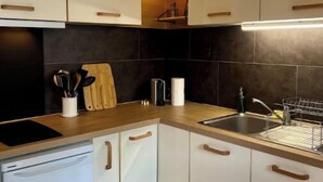 Una cucina moderna con mobili bianchi, un piano di lavoro in legno, un forno integrato e un lavello in acciaio inossidabile.