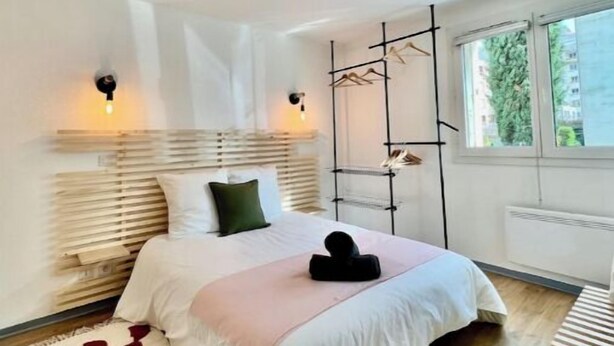 Una camera da letto con un letto, lampade sui comodini, una finestra e un termosifone.