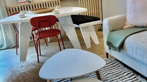 Un soggiorno moderno con un tavolo bianco, sedie rosse, un divano bianco e un tappeto decorato.