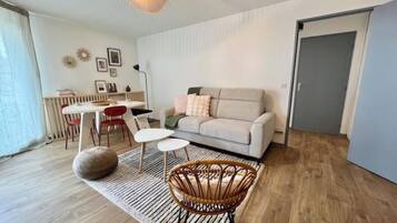 A modern living room with a sofa, a dining table, and chairs.